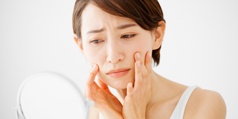 自分の顔のシワを確認する女性のイメージ