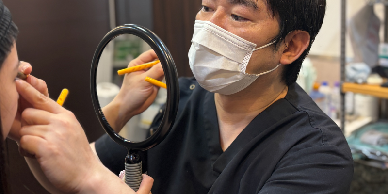 医師が患者のまぶたの状態を診察する様子