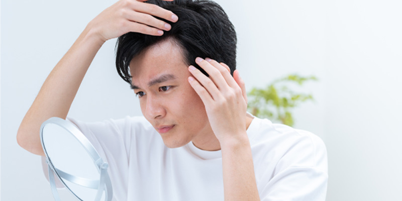 AGA治療の経過を鏡で確認する男性